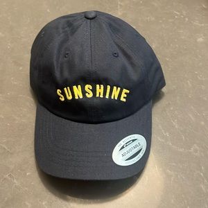 Navy blue adjustable hat with yellow writing with the word sunshine.